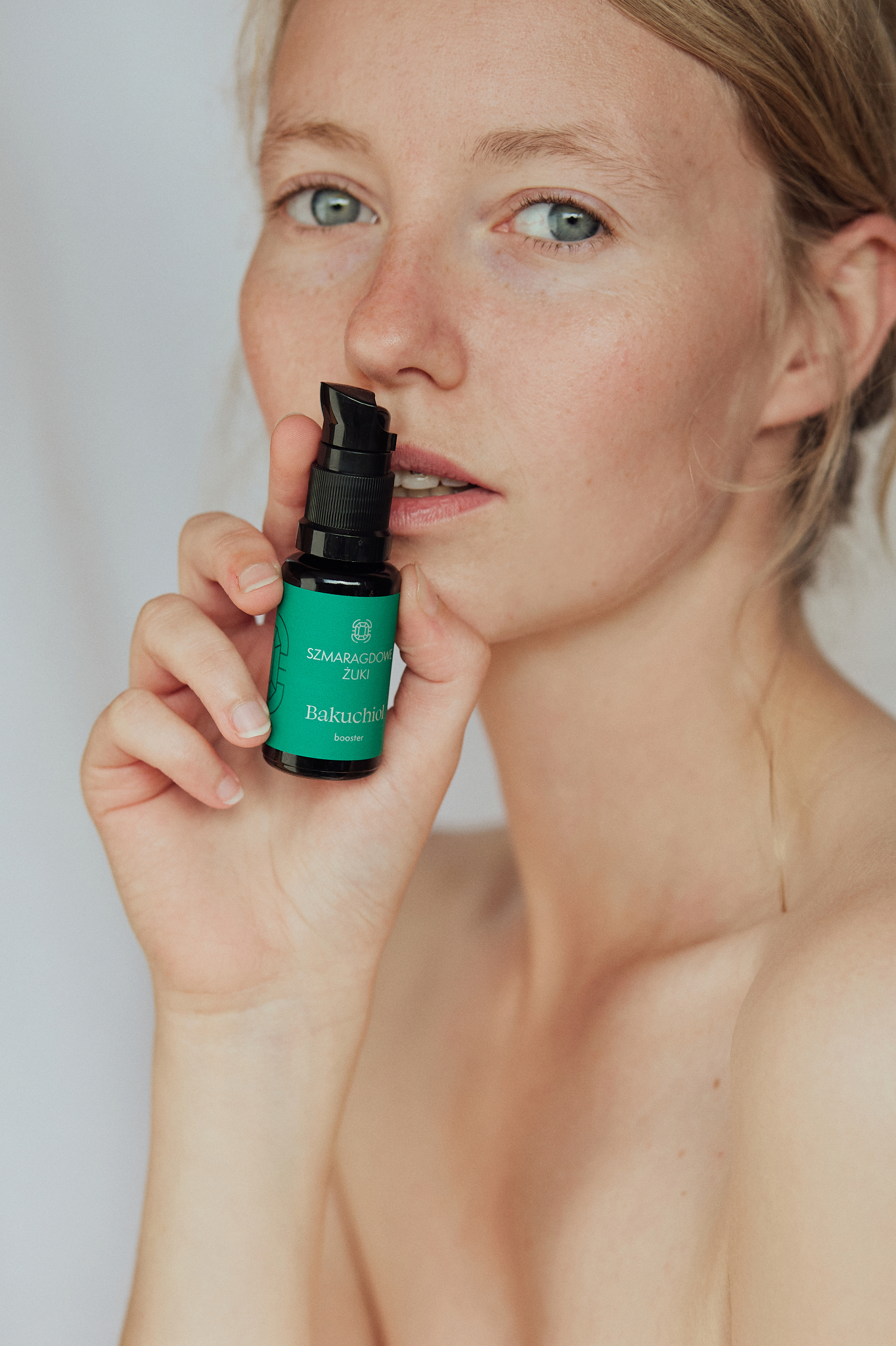 Kobieta trzymająca przy twarzy buteleczkę serum Bakuchiol booster Szmaragdowe Żuki
